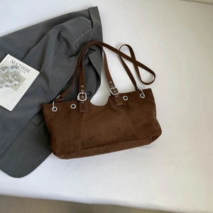 Close-up of deep brown suede tote with silver metal eyelets and adjustable buckle strap