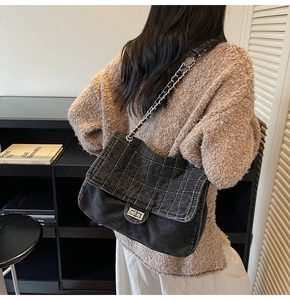Close-up of black denim chain bag with quilted lattice texture and silver metal lock