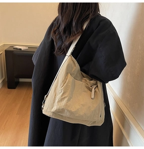 Gros plan d'un grand sac bandoulière en nylon kaki porté par un mannequin en intérieur