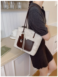 Detail of grey canvas tote bag with brown leather trim and chocolate-shaped charm detail
