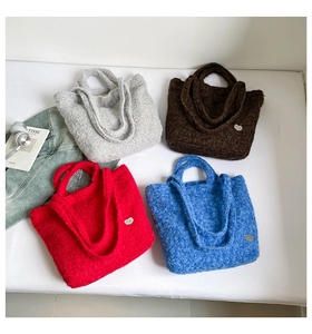Detailed overhead shot of plush tote bags in four colors with heart-shaped metal plates