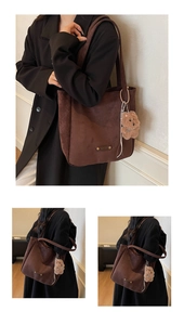 Detail of dark brown suede tote bag with metal logo and cute plush puppy charm pendant