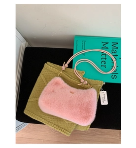 Detail van roze pluche schoudertas met leren riem op groen breigoed en kunstboeken