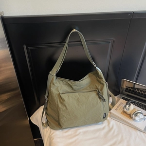 Détail du sac bandoulière en nylon vert olive avec grande poche zippée et tirette tissée