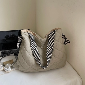 Detail of olive green quilted tote bag featuring a striped knot shoulder strap design