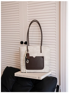 Detail view of the retro woven tote bag featuring a leather strap and chocolate charm