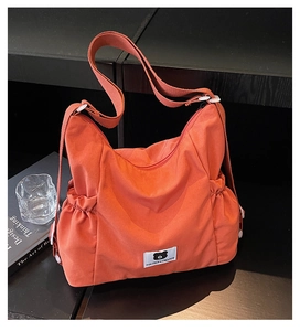 Detailed close-up of orange canvas tote featuring side drawstrings and bear logo label