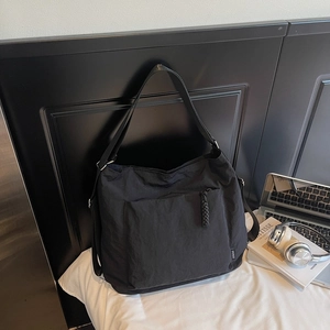 Gros plan du sac fourre-tout en nylon noir avec poche zippée et tirette tissée sur lin