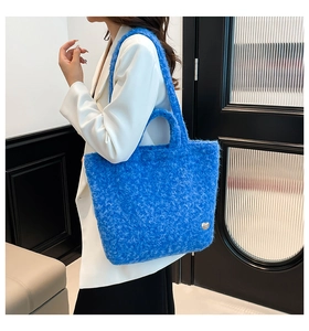 Detail view of electric blue plush tote bag featuring silver bean metal ornament