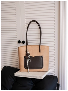 Close-up of retro woven tote bag with brown leather pocket and chocolate charm accessory
