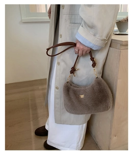 Détail d'un sac à bandoulière en peluche marron avec lanières en cuir et boucles dorées