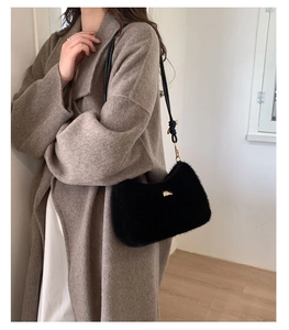 Gros plan du sac à bandoulière en peluche noire avec détails dorés élégants et lanière en cuir