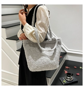 Detail of grey plush tote bag featuring thick faux shearling texture and metal logo plate