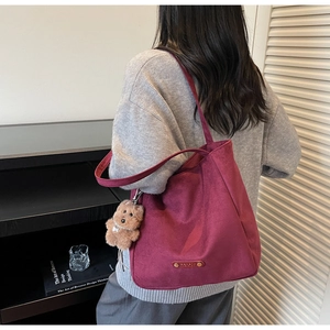 Détail du sac cabas bordeaux mat avec un charm chien en peluche et étiquette en cuir minimaliste