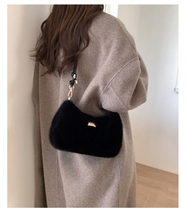 Détail d'un sac hobo en fausse fourrure noire avec logo doré et bandoulière réglable