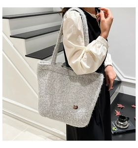 Close-up of grey plush fleece tote bag featuring heart-shaped metal logo and soft texture