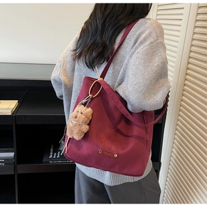 Détail du sac cabas en daim bordeaux avec pendentif ours et étiquette de marque