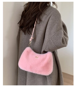 Détail du sac bandoulière rose en peluche avec logo doré et fine bandoulière élégante