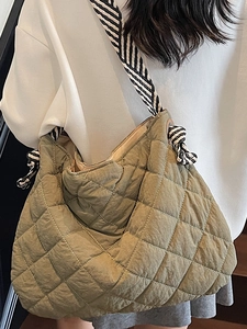 Quilted olive green tote bag with patterned wide shoulder strap shown on a model
