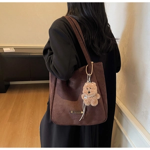 Détail d'un sac cabas en daim marron avec charm chien en peluche et étiquette en cuir