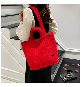 Detail view of red faux fur tote bag with heart charm and shoulder strap in casual setting