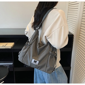 Rear view of a model wearing a grey high-density nylon tote bag with drawstring side pockets