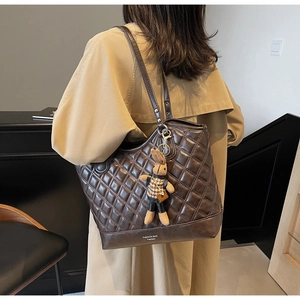 Detail view of coffee brown quilted tote bag with a small plaid bunny charm accessory