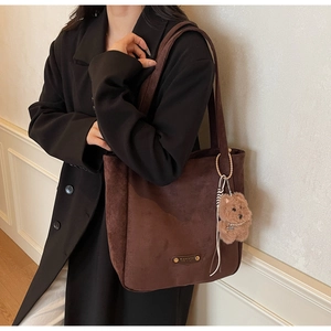 Détail d'un sac cabas en daim marron foncé avec un pendentif chiot en peluche doux