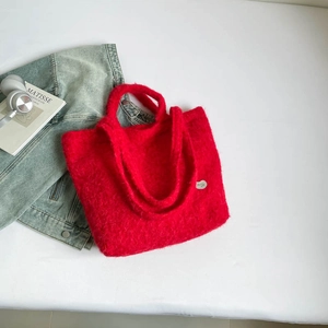 Flat lay of red fuzzy plush tote bag with denim jacket and stylish headphones