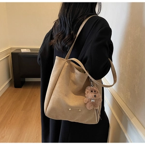 Mannequin portant un sac cabas en daim camel avec charm chien en peluche et logo en métal