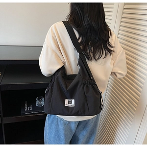 Detail of black canvas tote bag showing side drawstring design and Myron Bear logo patch