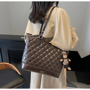 Quilted tote bag detail with rabbit charm and adjustable strap shown on shoulder