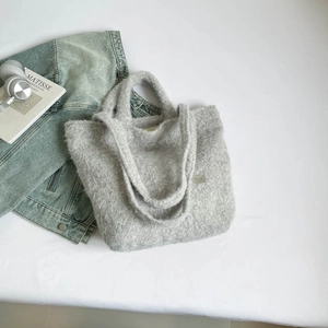 Detailed close-up of a grey fuzzy knit tote bag with plush texture in a casual lifestyle setting