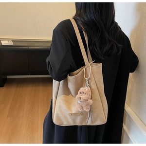 Détail du sac cabas en daim kaki avec charm chien en peluche et logo en métal