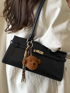 Minimalist black matte leather shoulder bag with gold buckle and plush bear pendant