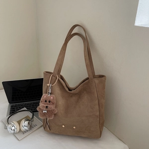 Sac fourre-tout en daim marron avec pendentif chien en peluche sur bureau avec ordinateur