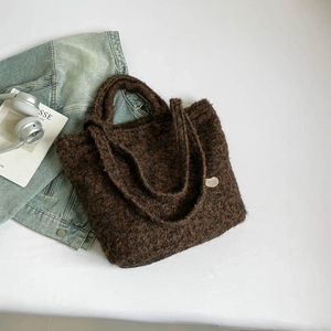 Detail of brown plush tote bag showing fuzzy grain texture and round metal logo