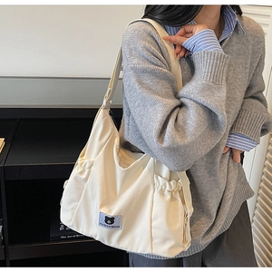 Close-up detail of cream canvas tote bag with Myron Bear logo and elastic side pocket