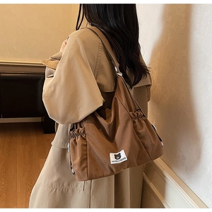 Detail of dark brown canvas tote bag with side drawstring and Myron Bear woven label