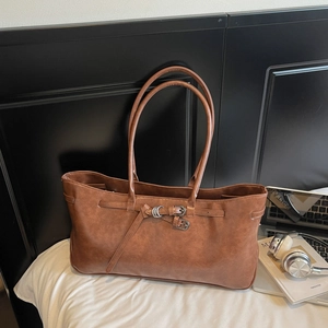 Detailed macro view of vintage brown leather texture and silver buckle accents on the tote bag