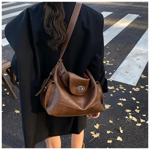 Brown oil wax leather tote bag shown on shoulder with silver twist lock and large capacity