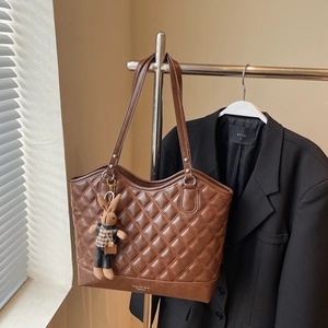 Detailed quilted leather pattern of the brown tote bag with a cute rabbit charm accessory