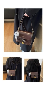 Detail view of brown glossy leather crossbody bag with knot decor and white plush charm