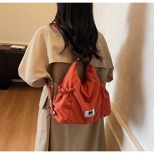 Detail view of large orange canvas shoulder bag with drawstring edges and bear logo label