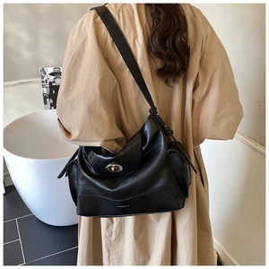 Detail of black leather tote bag featuring a vintage metal swivel lock and side pocket