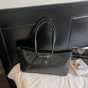 Detailed view of black PU leather tote bag with silver buckle and shoulder straps