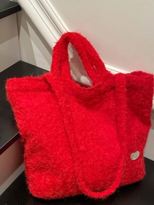Chic red plush tote bag with furry texture and silver heart detail for stylish commuting