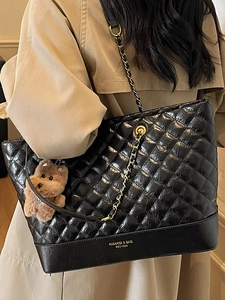 Classic black quilted tote bag with gold chain strap and cute plush dog charm