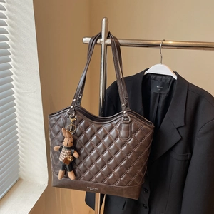 Close-up of diamond-quilted brown tote bag with cute rabbit charm and fashion logo