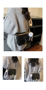 Detail of black crossbody bag with golden metal charm and plush white doll accessory